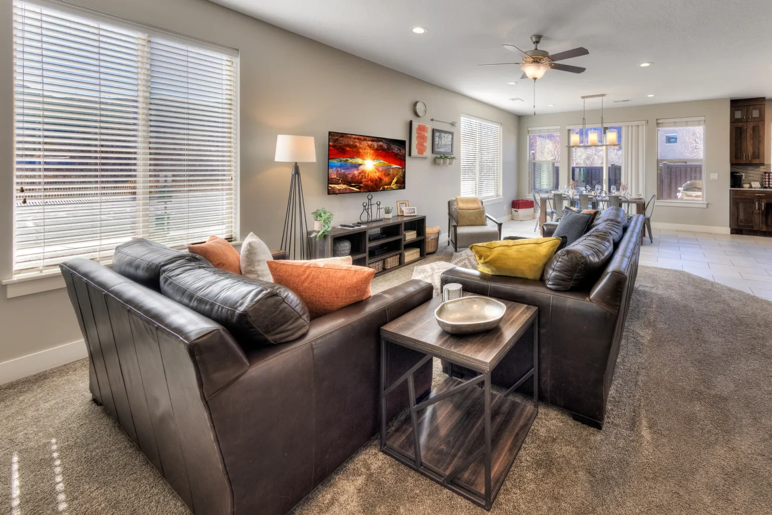 Sunlit Open-Concept Living Area with Leather Sofas and Warm Wood Accents Bright open-plan living and dining area in an end-unit Entrada Moab townhome featuring natural side-window lighting.