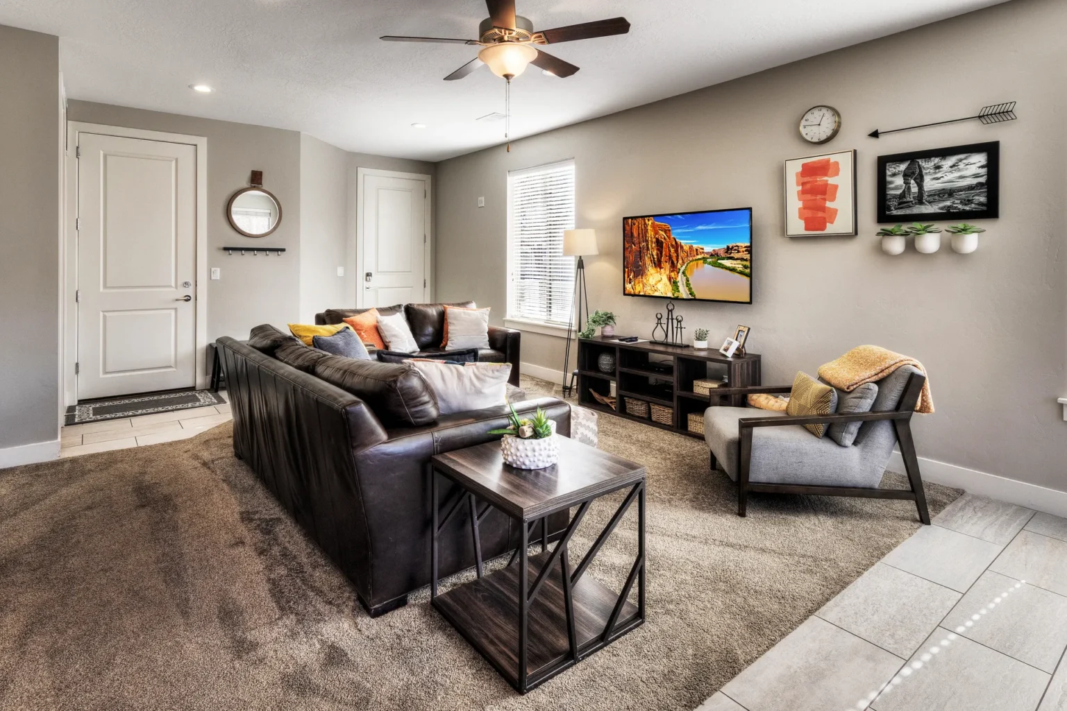 Cozy Modern Living Room with Dark Leather Sofa and Wall TV Modern designer living room in Entrada Moab townhome 417 featuring leather seating, local canyon art, and 9-foot ceilings.
