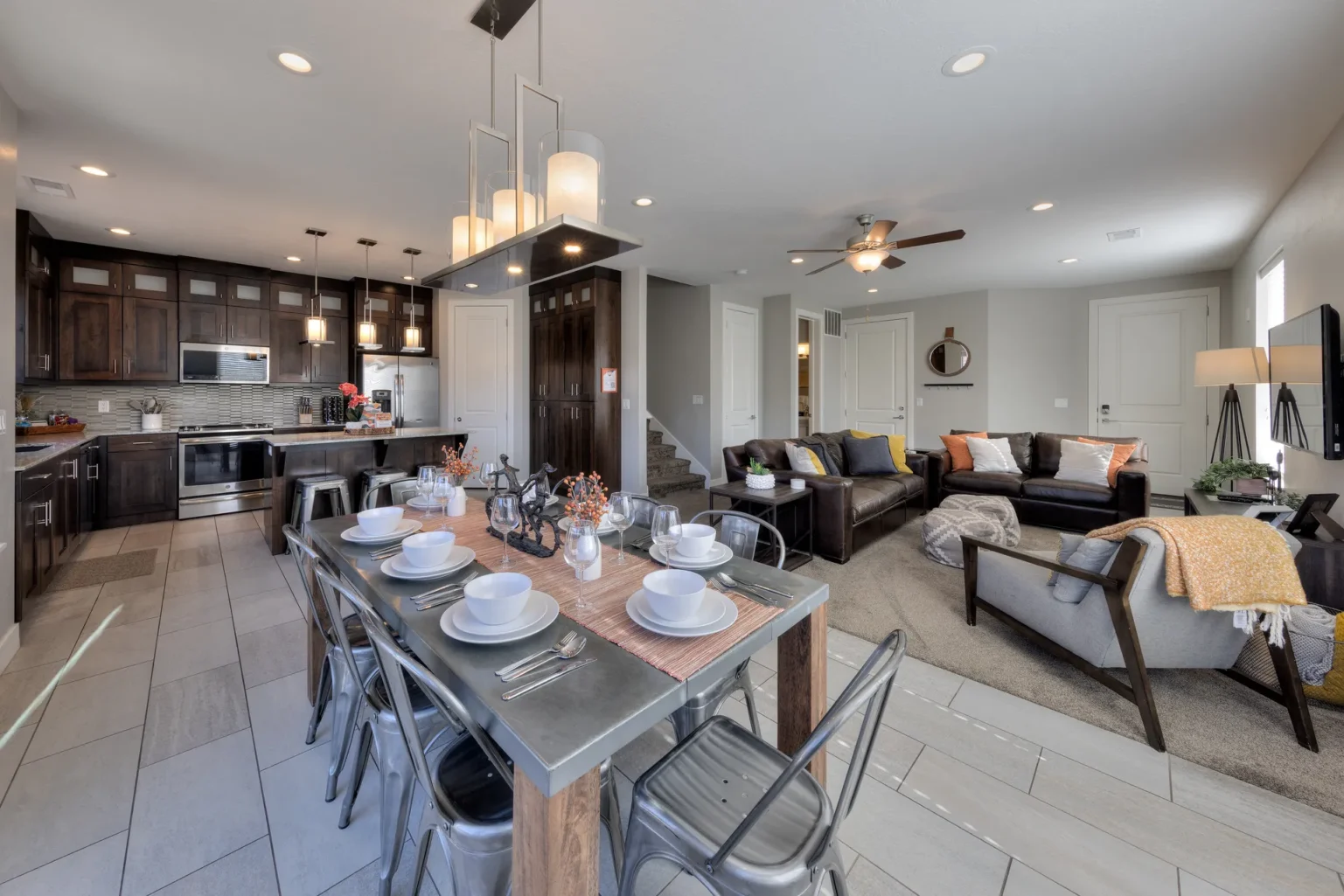 Modern Open-Concept Living: Dark Wood, Stainless Steel, and Glass Light Gourmet kitchen and dining area in Moab townhome with dark wood cabinetry, breakfast bar seating, and stainless steel appliances.