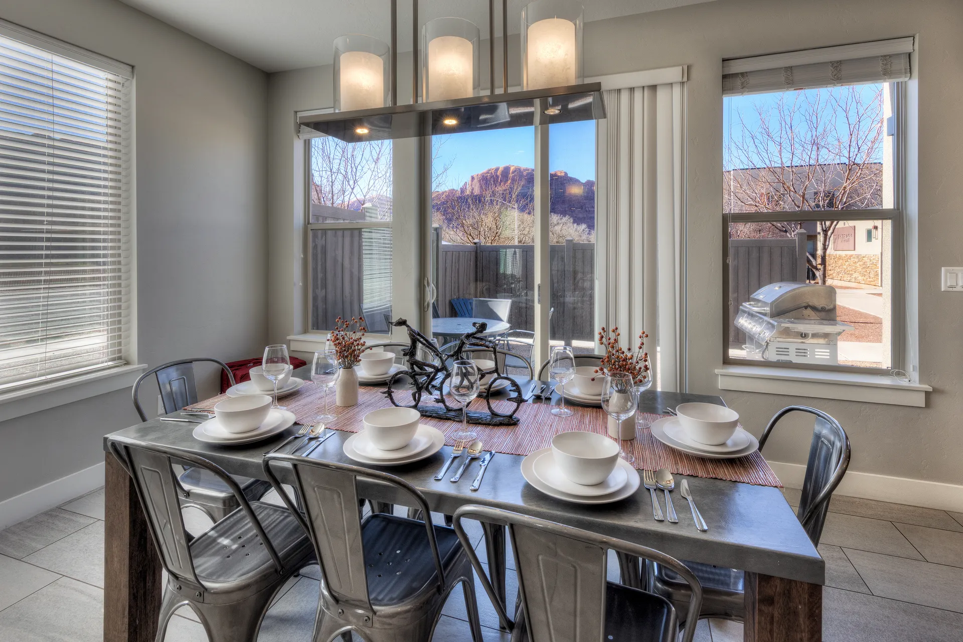 Dining table with a view of red rock cliffs through the glass patio door in an away-facing Entrada Moab townhome.