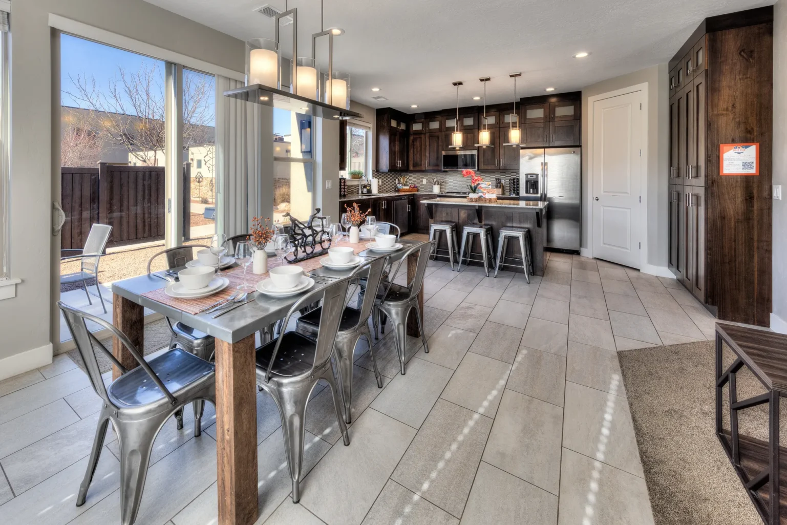 Open-concept kitchen and dining area with long table and glass doors Social kitchen and dining hub in an end-unit Entrada Moab townhome with side-wall natural light and breakfast bar seating.