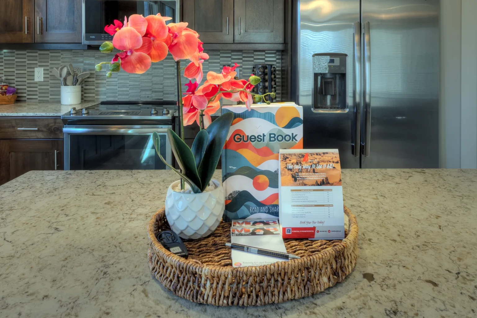 021-Entrada-Moab-417-Living-Dining-Kitchen Personal guest book and welcome tray on the granite island of a luxury Moab vacation rental.