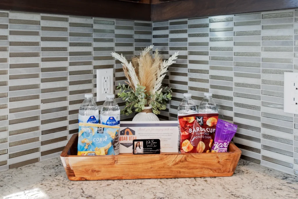 Close-up of a welcome tray in a Moab vacation rental with snacks, bottled water, and local guide brochures.