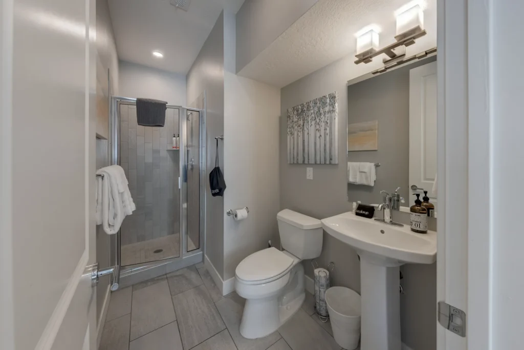 Modern main-floor bathroom in Entrada Moab 417 featuring a walk-in glass shower, pedestal sink, and professional finishes.