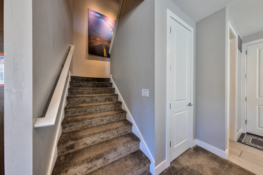 Carpeted staircase in a luxury Moab rental featuring a large Milky Way landscape photograph on the landing.
