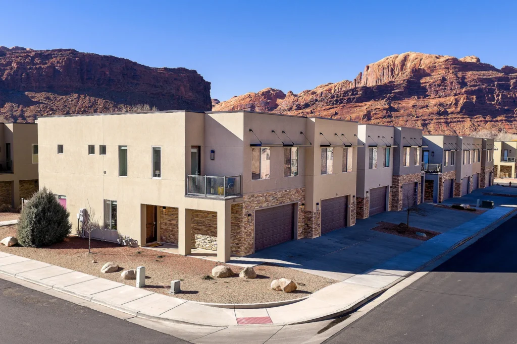 Row of modern luxury townhomes in Moab with a dramatic red rock mountain backdrop.