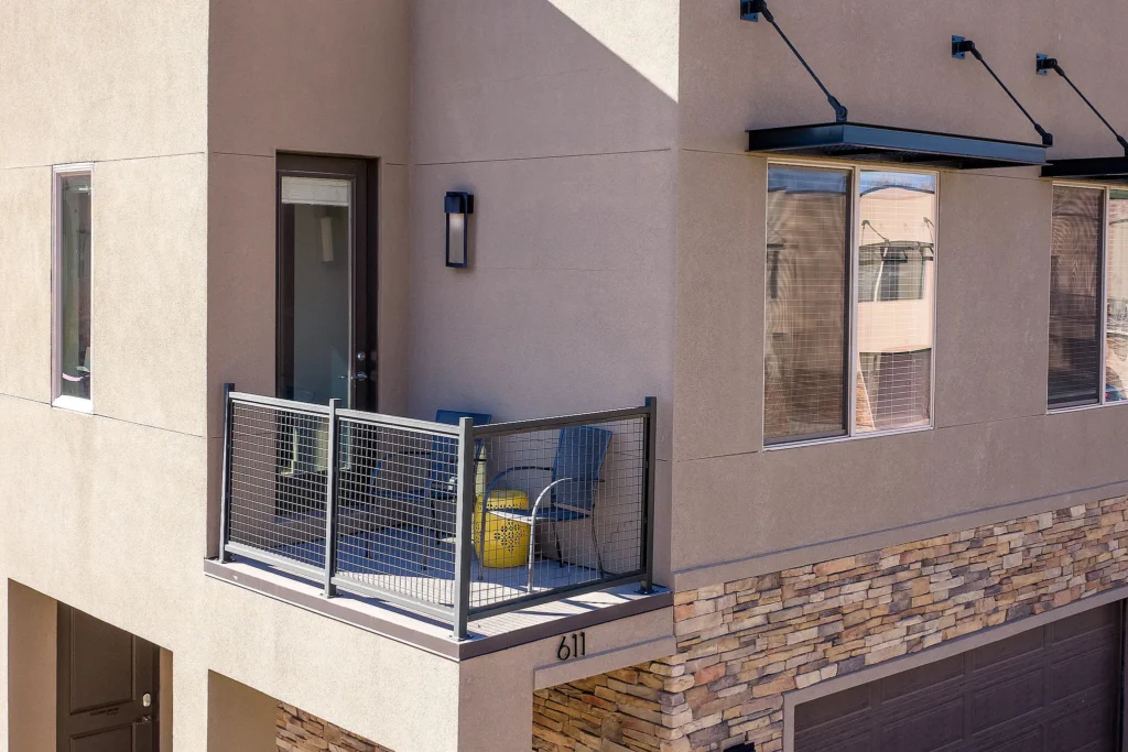 Close-up of a private second-story patio with seating and modern facade at Entrada 611.