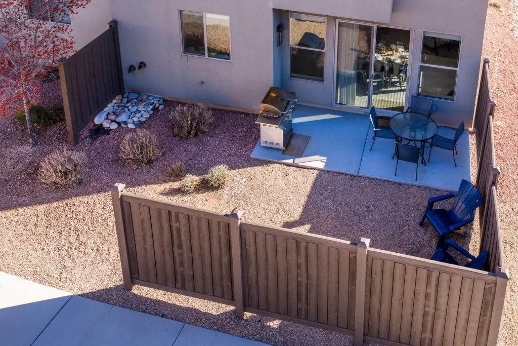 Private fenced patio at Entrada Moab 417 with a propane grill, outdoor dining table, and red rock views.