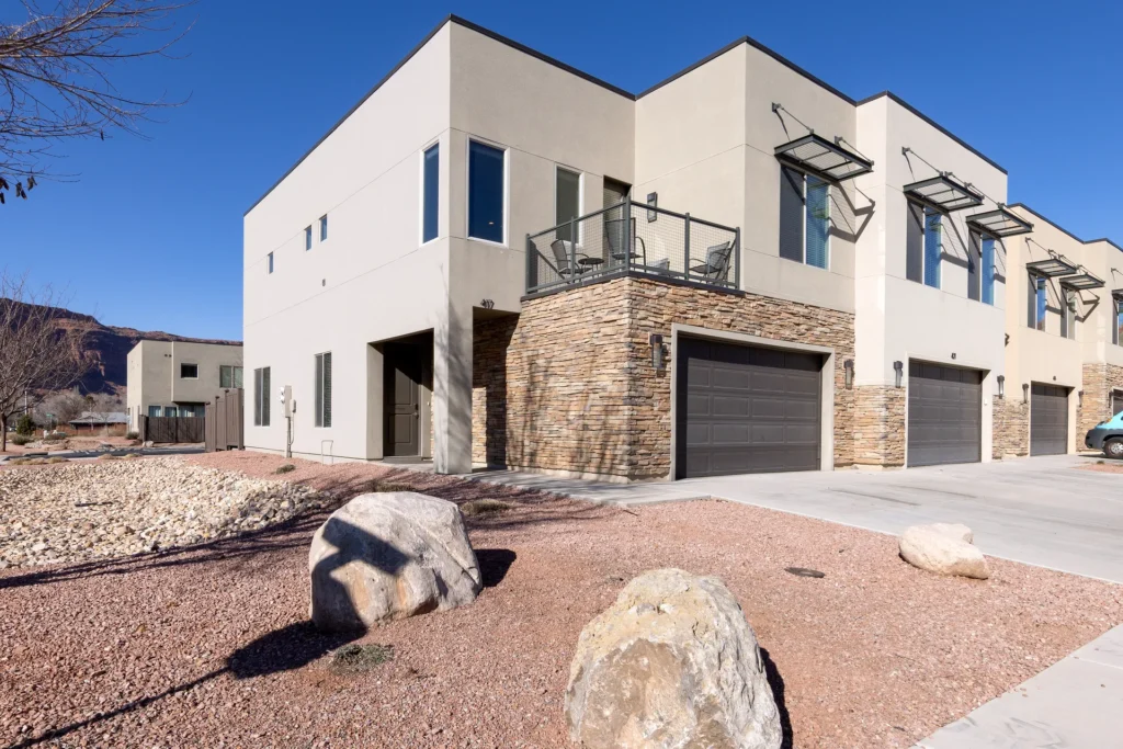 Modern corner-unit townhome exterior at Entrada Moab with red rock canyon backdrops and desert landscaping.