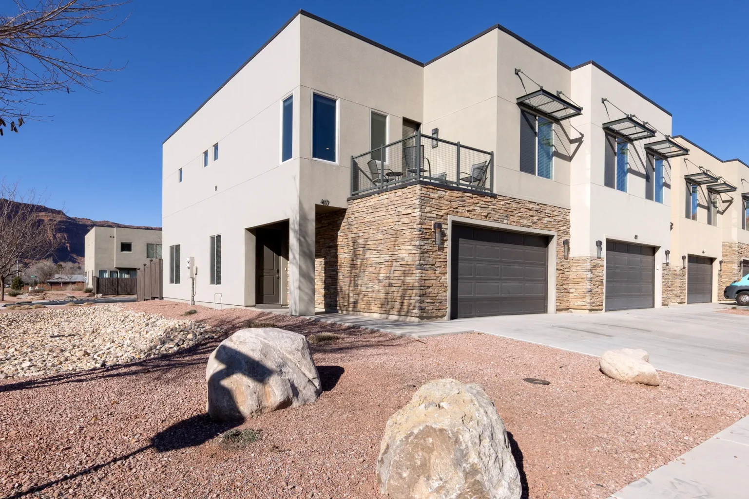 006-Entrada-Moab-417-Exterior Modern corner-unit townhome exterior at Entrada Moab with red rock canyon backdrops and desert landscaping.