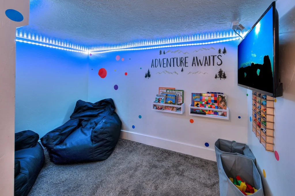 Kids' playroom in Entrada 611 with bean bags, books, and a TV showing Turret Arch.