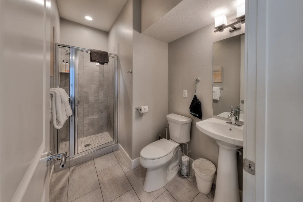 Main level full bathroom with walk-in shower and pedestal sink in a Moab luxury home.