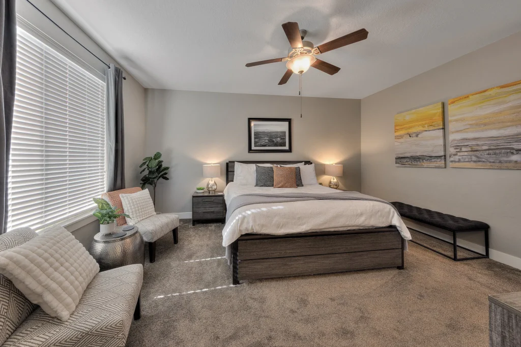 Master bedroom seating area with desert-inspired art and large window in a Moab luxury rental.