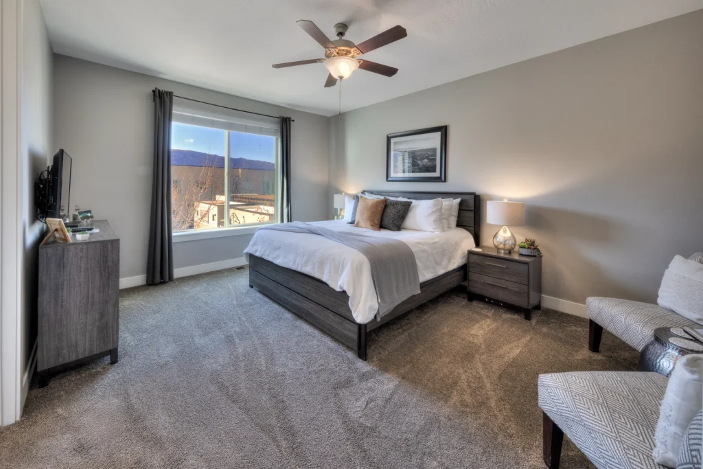 Spacious king master suite in Entrada Moab 417 featuring a seating area, ceiling fan, and red rock views.