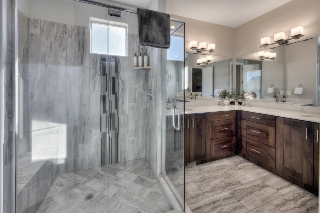 Modern glass walk-in shower with designer tile work and built-in bench in an Entrada Moab townhome.