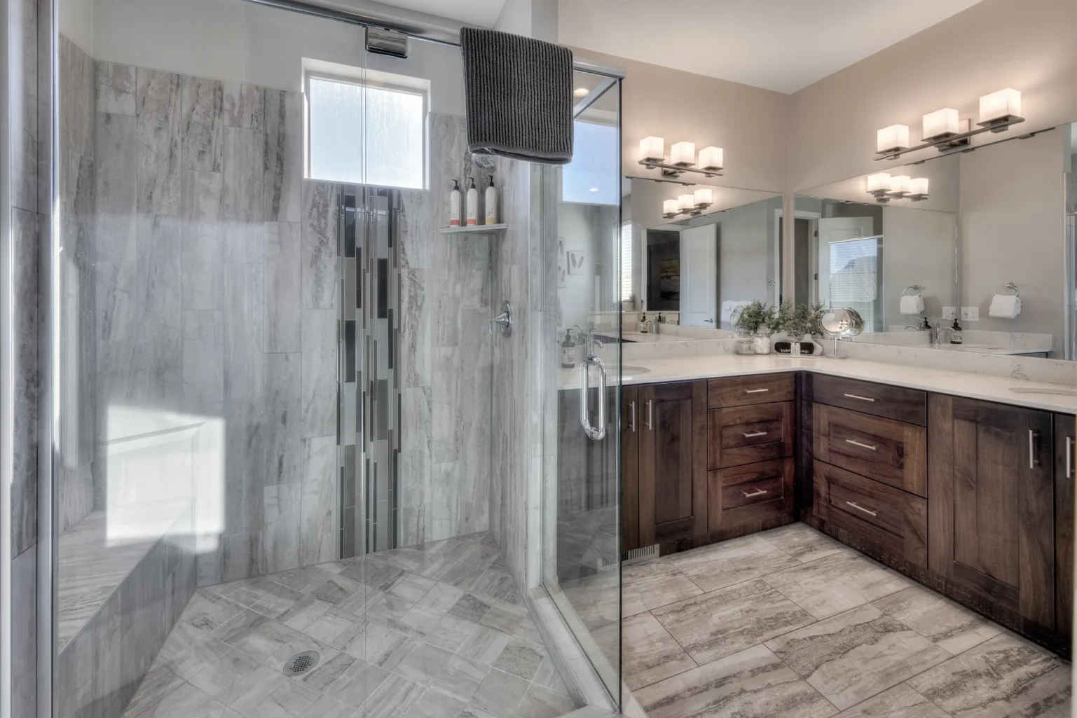 Modern bathroom with glass shower, gray marble tiles, and dark wood vanity Modern glass walk-in shower with designer tile work and built-in bench in an Entrada Moab townhome.