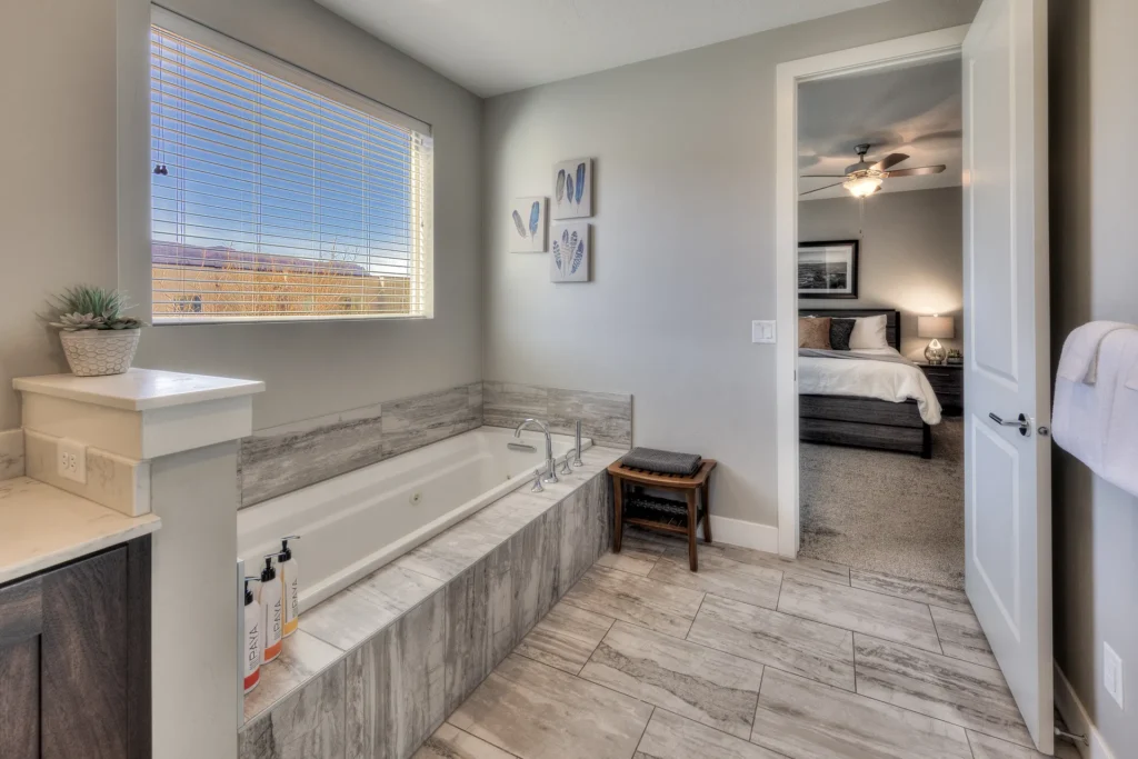 Deep jetted soaking tub in a luxury Entrada Moab master bath with a view window of the red rock landscape.