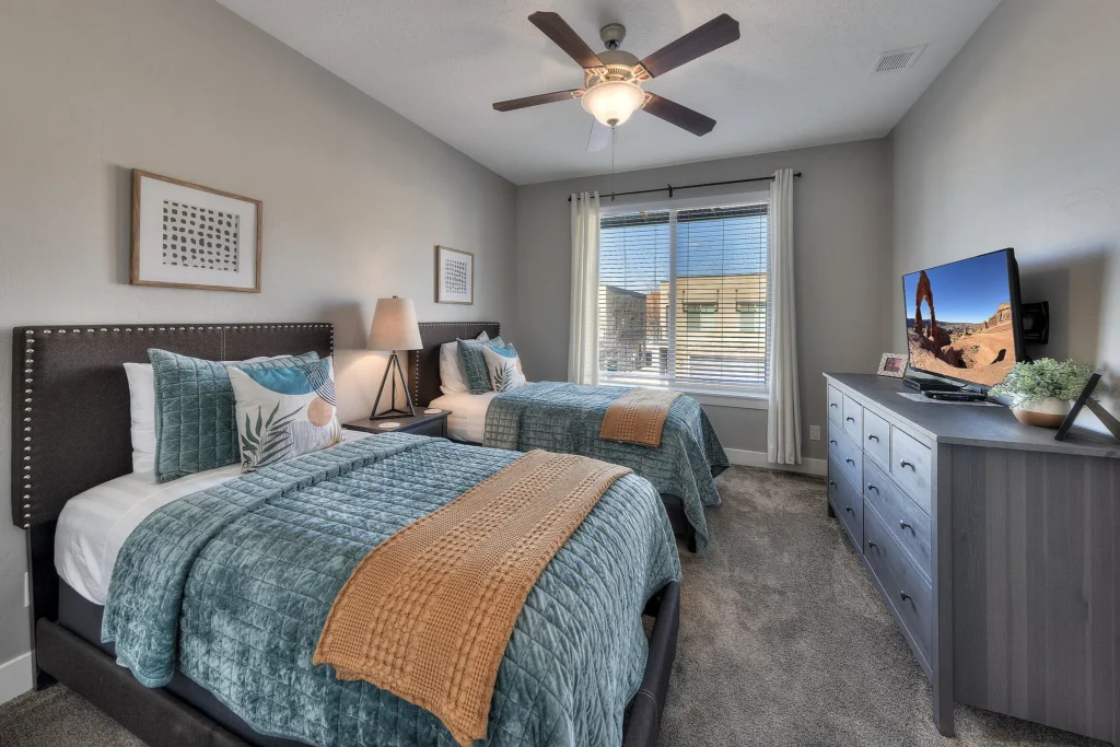 Twin bedroom in Moab luxury rental with smart TV showing Delicate Arch.