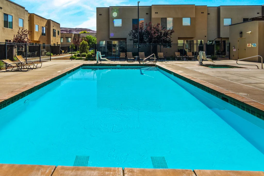 Sparkling blue community pool at Entrada Moab under a clear desert sky, viewed from the sun deck.