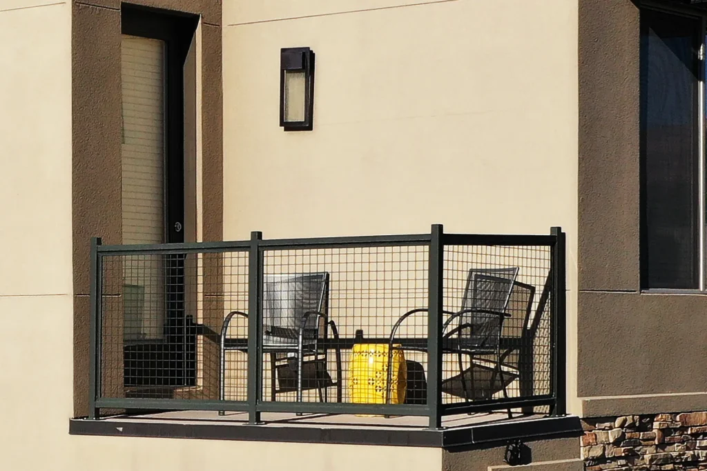 Close-up of private second-story balcony with metal mesh railing and seating in Moab.